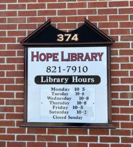 signage for Hope Library with telephone number and library hours.