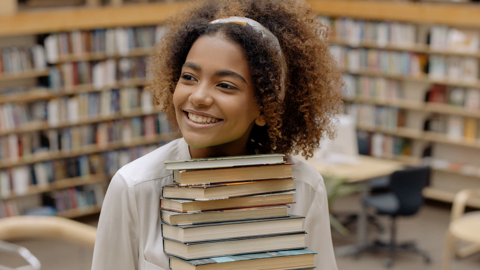 smiling girl holding a stack of books
